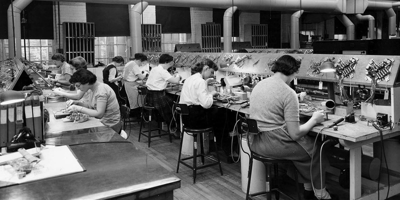 Photo of Sprague employees on the factory floor working on parts for capacitors.